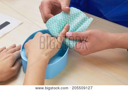 Woman hands receiving manicure. Beautician making spa procedure for clients hands. Manicurist wipe finger to client before manicure.