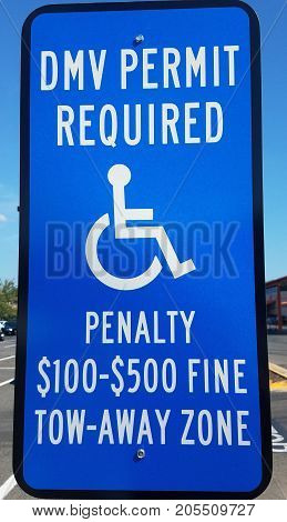a blue DMV permit required sign with wheelchair and penalty information