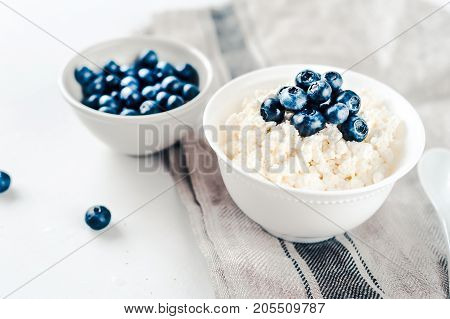Fresh cottage cheese with blueberries on wood white