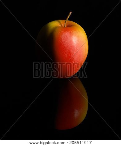 Studio photography of a fresh red apple in black reflective back
