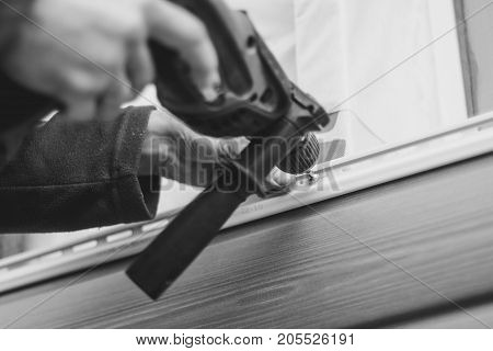 A worker installs panels beige siding on the facade of the house