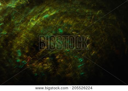 Abstract background of yellow and green waves in motion on black. Bokeh of defocused crankles spinning into spiral, blurred neon leds, similar to toxication and disordered stomach concept