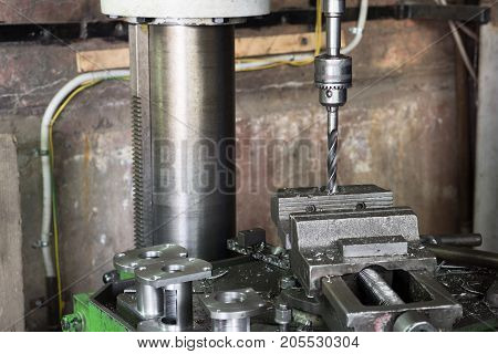 Drilling machine. The drill bit is installed in the drill chuck. Machine vice, metalworking shop.