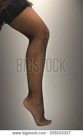 Sexy female legs in fishnet pantyhose stockings standing on toe cap isolated.