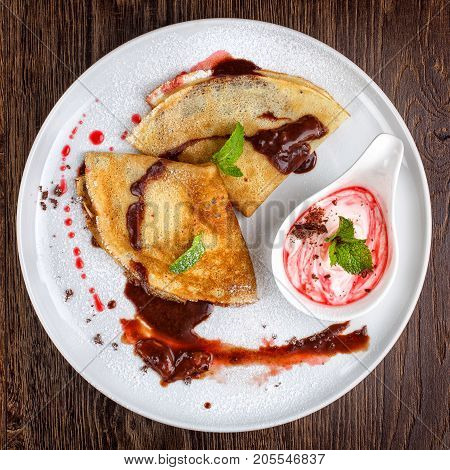 Golden pancakes with sweet chocolate sauce on a dessert plate, fuul focus