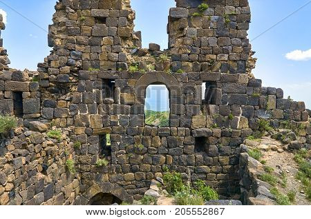 Ruined wall of the medieval armenian fortress Amberd with loopholes and windows