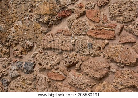 Ancient stone wall. Masonry of old stones and bricks. Beautiful unusual background.