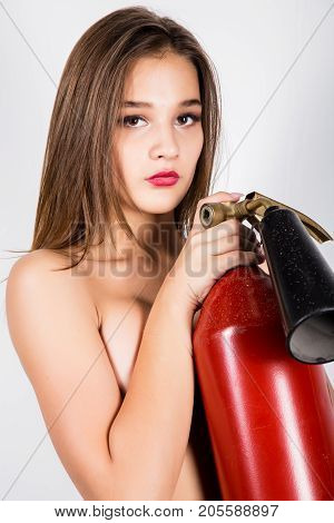 Sexy sensual female firefighter with a red fire extinguisher.