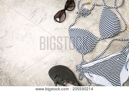 Female summer striped bikini swimsuit, clothes and accessories collection on gray background. Flat lay, top view