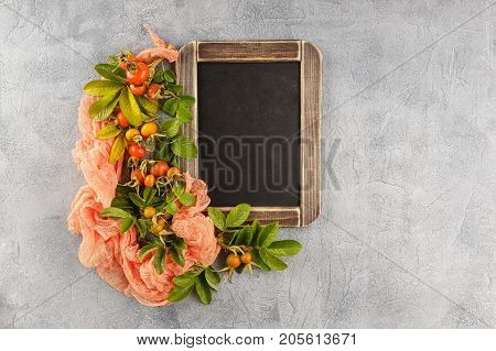 Blackboard and dogrose berry Autumn decorations. Top view space for text on the board.