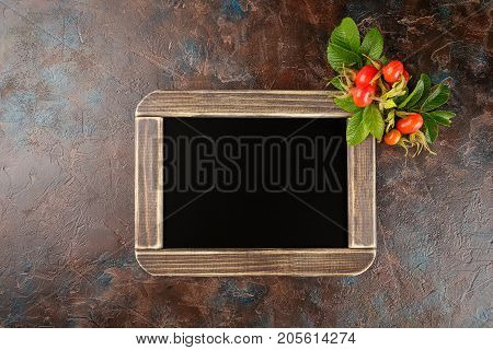 Black chalkboard and dogrose berry Autumn decorations. Top view space for text on the board