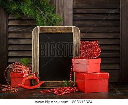 Chalkboard and Christmas decorations and red gifts boxes on dark background