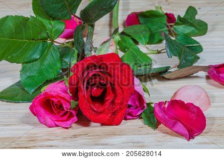 leaf of rosepink roses and red rose flowers in the pinewood table