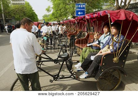 BEIJING, CHINA - MAY 01, 2013: Unidentified rickshaw transports passengers at Futong street next to the Houhai lake in Beijing, China.