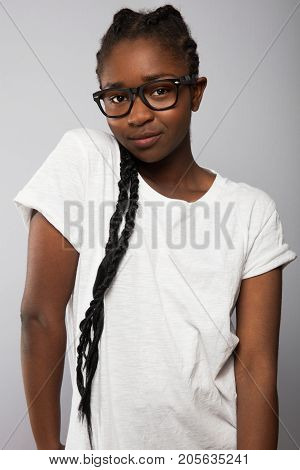 Portrait of confident female model with braided hair standing over gray background