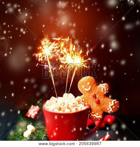 Christmas Card with hot cocoa red mug sparkling bengal fire work lights falling snow and gingerbread man cookie and festive decorations. Christmas Cozy home concept.