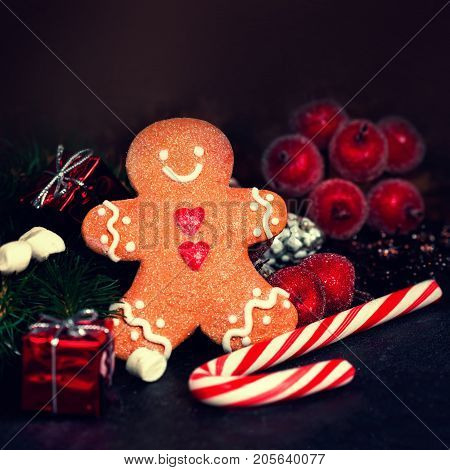 Christmas composition with Christmas gift Gingerman cookie fir tree branches xmas holiday decorations and festive symbols on dark background with copy space for your design or Happy New Year text