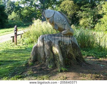 Graasten Denmark - August 22 2009: Carp carved out of dead elm tree at forrest entrance