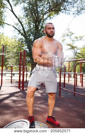 Sporty and healthy muscular man exercising outdoors. Sexy young man with a muscular body on a natural background. Strong and perfect male body.