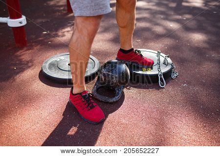 A strong man with sexy body is doing exercises on his feet. A handsome young man lifts weights with his feet in the park.