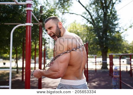 Sporty and healthy muscular man exercising outdoors. Sexy young man with a muscular body on a natural background. Strong and perfect male body.