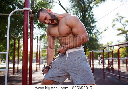 Sporty and healthy muscular man exercising outdoors. Sexy young man with a muscular body on a natural background. Strong and perfect male body.