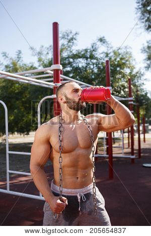 Sporty and healthy muscular man exercising outdoors. Sexy young man with a muscular body on a natural background. Strong and perfect male body.