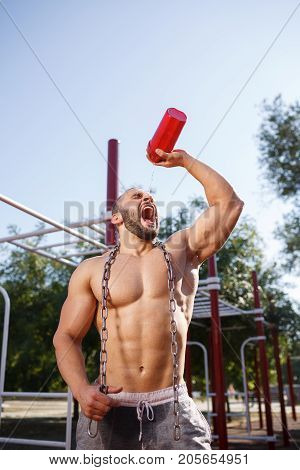 Sporty and healthy muscular man exercising outdoors. Sexy young man with a muscular body on a natural background. Strong and perfect male body.