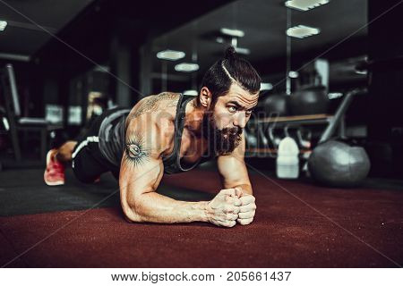 Plank it. Confident muscled young man wearing sport wear and doing plank position while exercising in gym.