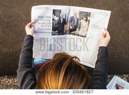PARIS FRANCE - SEP 25 2017: Woman reading international newspaper about Donald Trump Rex Tillerson and Nikki Halley