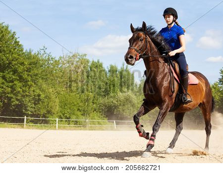 Female jockey galloping on horseback at racetrack during show jumping