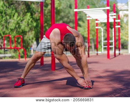 Sporty and healthy muscular man exercising outdoors. Sexy young man with a muscular body on a natural background. Strong and perfect male body.
