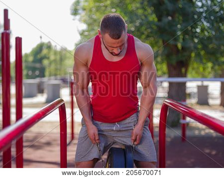 Sporty and healthy muscular man exercising outdoors. Sexy young man with a muscular body on a natural background. Strong and perfect male body.