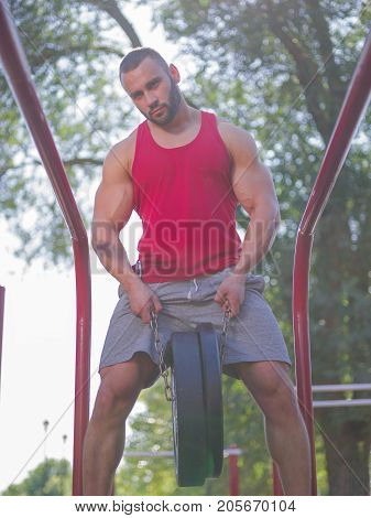 Sporty and healthy muscular man exercising outdoors. Sexy young man with a muscular body on a natural background. Strong and perfect male body.