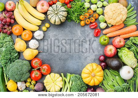 Rainbow colour vegetables arranged in a circle on the dark grey background, copy space for text in the middle, top view, selective focus