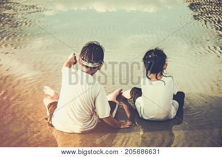 Asian Children Digging In The Sand. Concept Of Connecting Children With Nature.