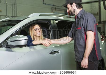 An auto mechanic and female customer in garage