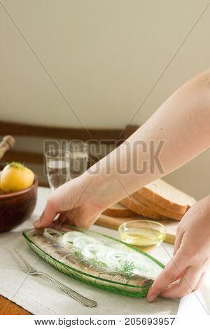 Herring with onions and dill in a glass plate served with boiled potatoes bread and vodka. Soviet life. Rustic style selective focus.