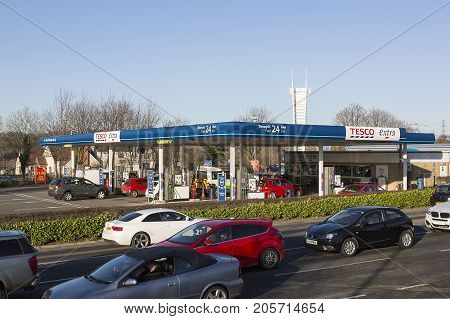 Swansea, UK: December 28, 2016: Cars queue to leave a shopping mall. A Tesco petrol station is behind with customers refueling their vehicles.