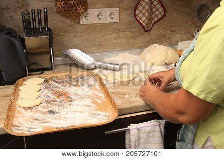 Senior woman baking pies in her home kitchen.Grandma cooks pies. Home cooked food. omemade mold cakes of the dough in the women's hands. The process of making pie dough by hand.