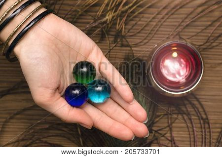 Fortune teller female hands with talisman gems on wooden table and candle. Divination concept.