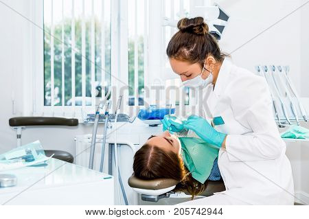 Female dentist checking up patient teeth with metal braces at dental clinic office. Medicine, dentistry and health care concept. Dental equipment