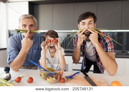 An old man, a man and a boy, make faces. The old man and the man made a mustache from the green, the boy made himself the eyes of tomatoes