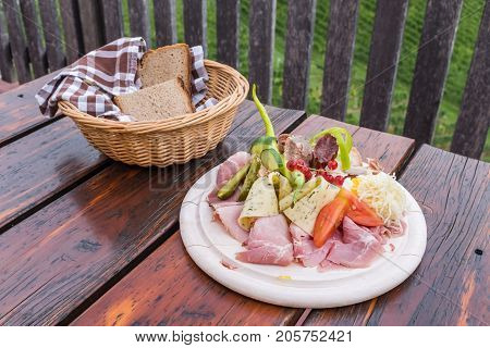 Traditional Brettljausn with bread and a lot of cold cuts on wooden table on south Styrian vine route in Austria