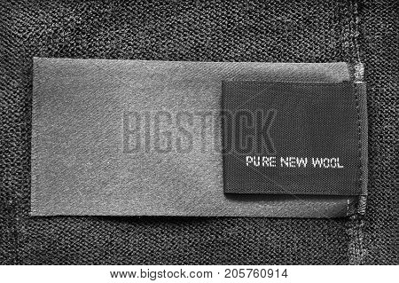 Textile clothes label lettered pure new wool on black wool background