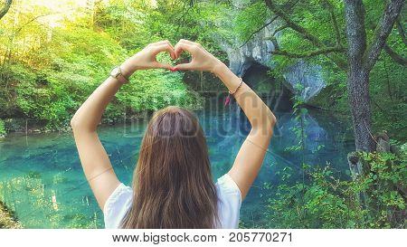 Young woman holding heart-shape for the beautiful nature.