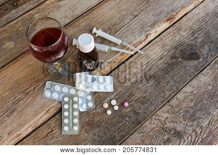 Medication and alcohol  on old wooden background.