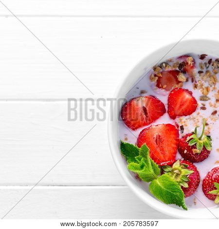 Huge bowl of granola with strawberries and mint leaves, additional textspace left on side, topview