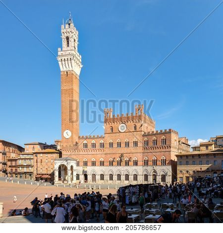 SIENA,ITALY - JULY 23,2017 : Tourists at Piazza del Campo next to the Palazzo Publico on the medieval city of Siena