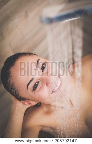 Young beautyful woman under shower in bathroom.